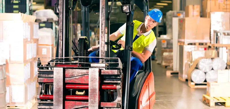 manutentionnaire sur un chariot élévateur dans un entrepôt